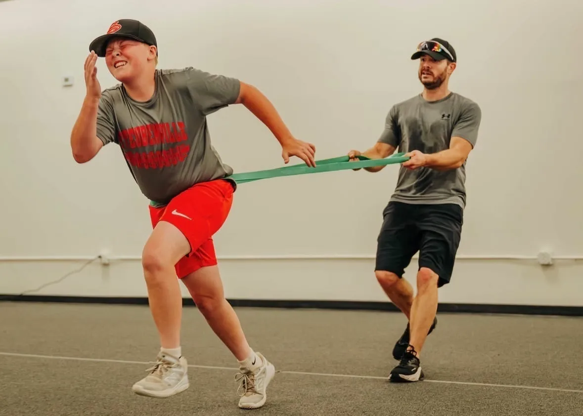 Coach guiding a young athlete through a resistance-band sprint