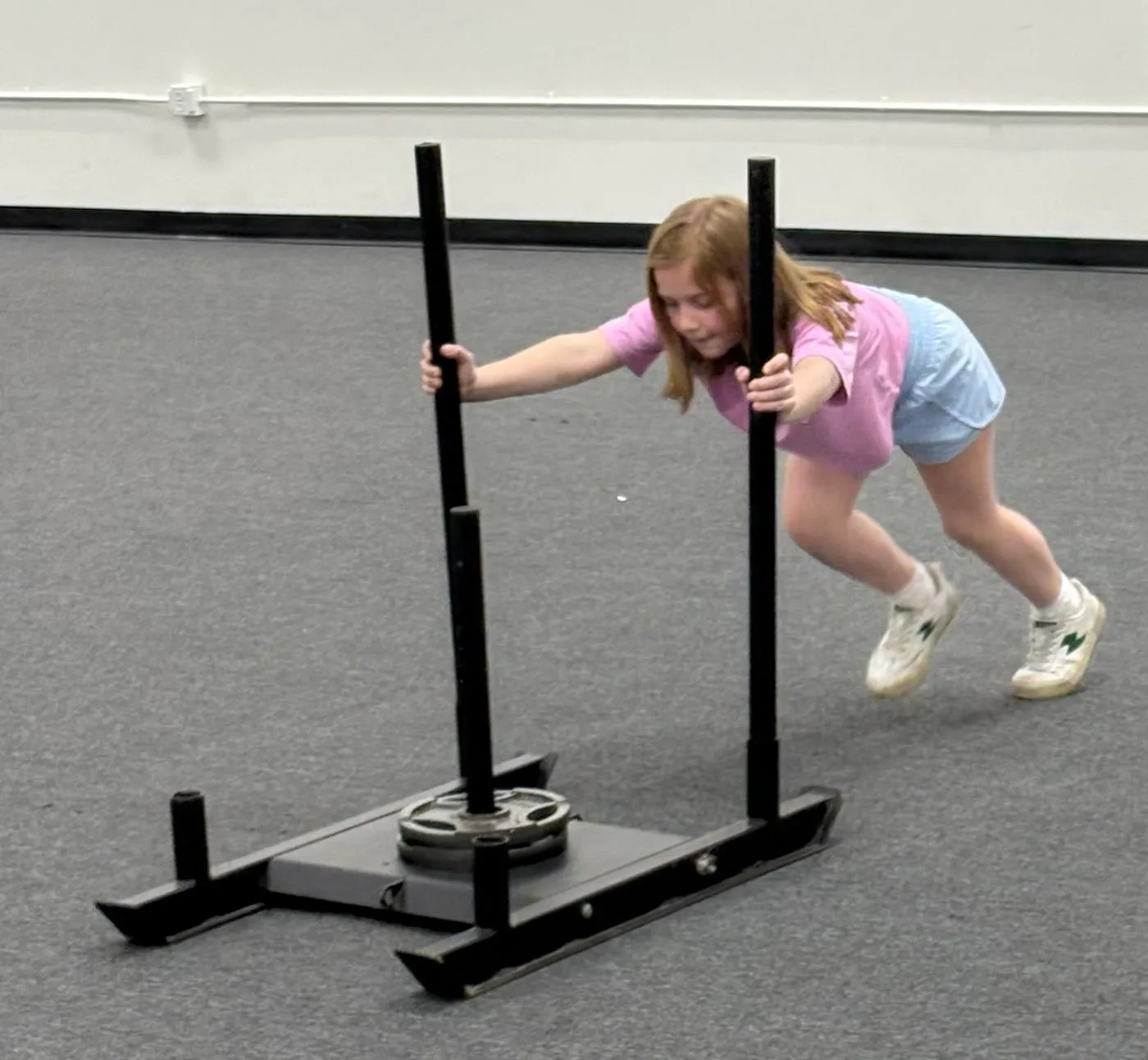 Young athlete pushing a training sled