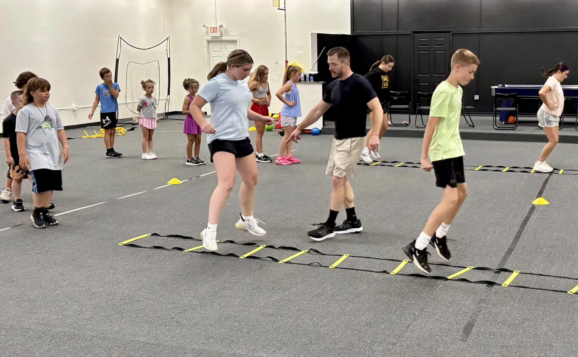 Coach leading kids through agility ladder drills at Velocity Sports Lab