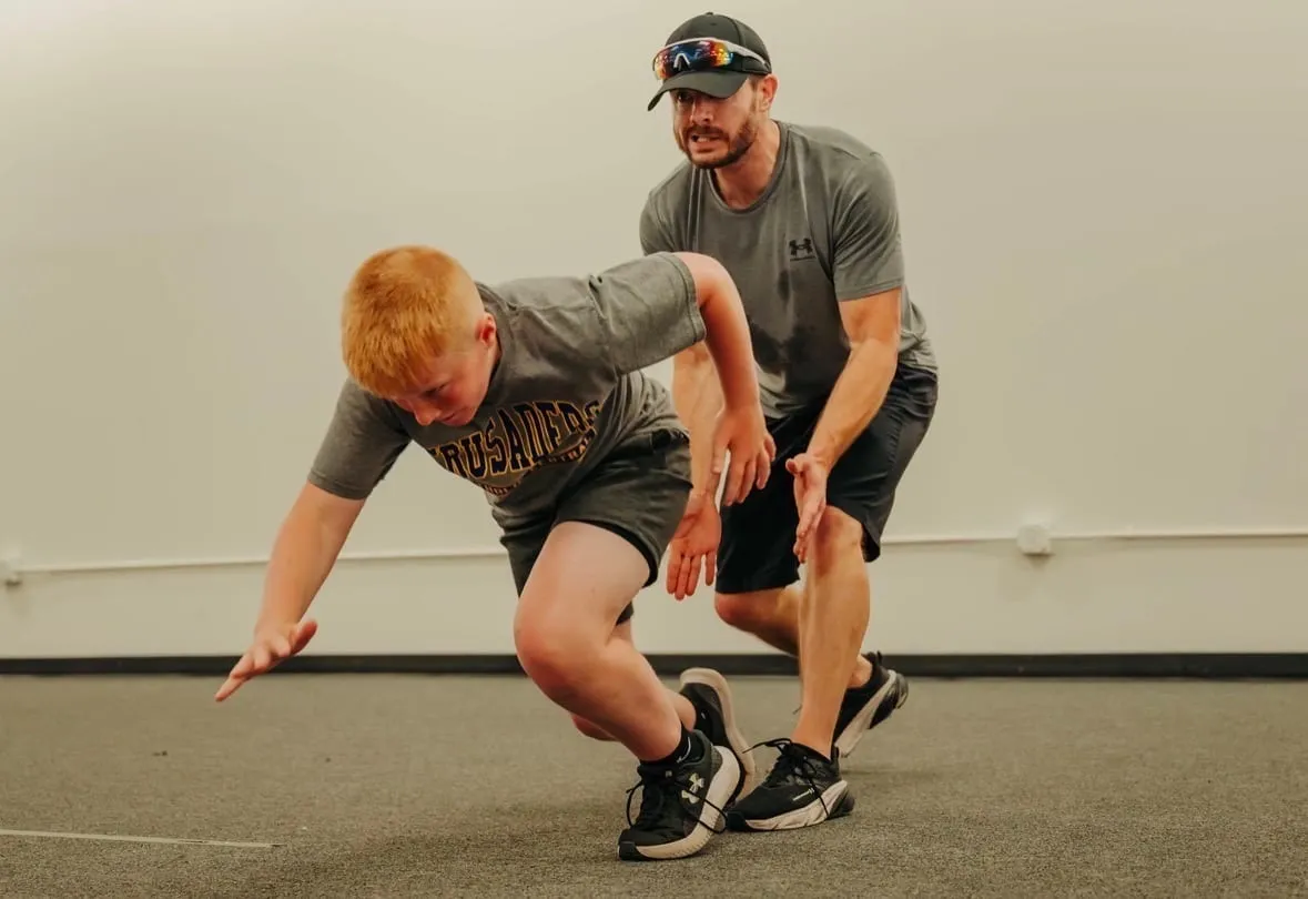 Coach starting a young athlete in a sprint drill